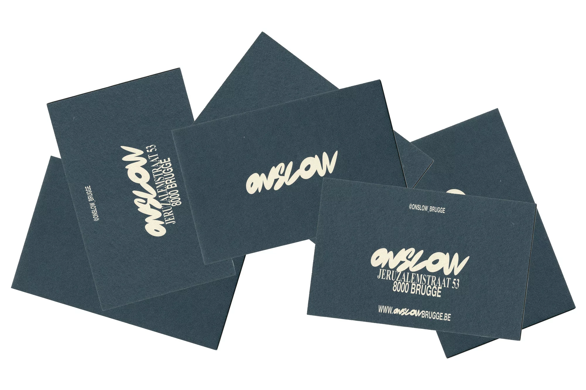 Scattered dark grey business cards featuring cream-colored typography for Onslow on a white background