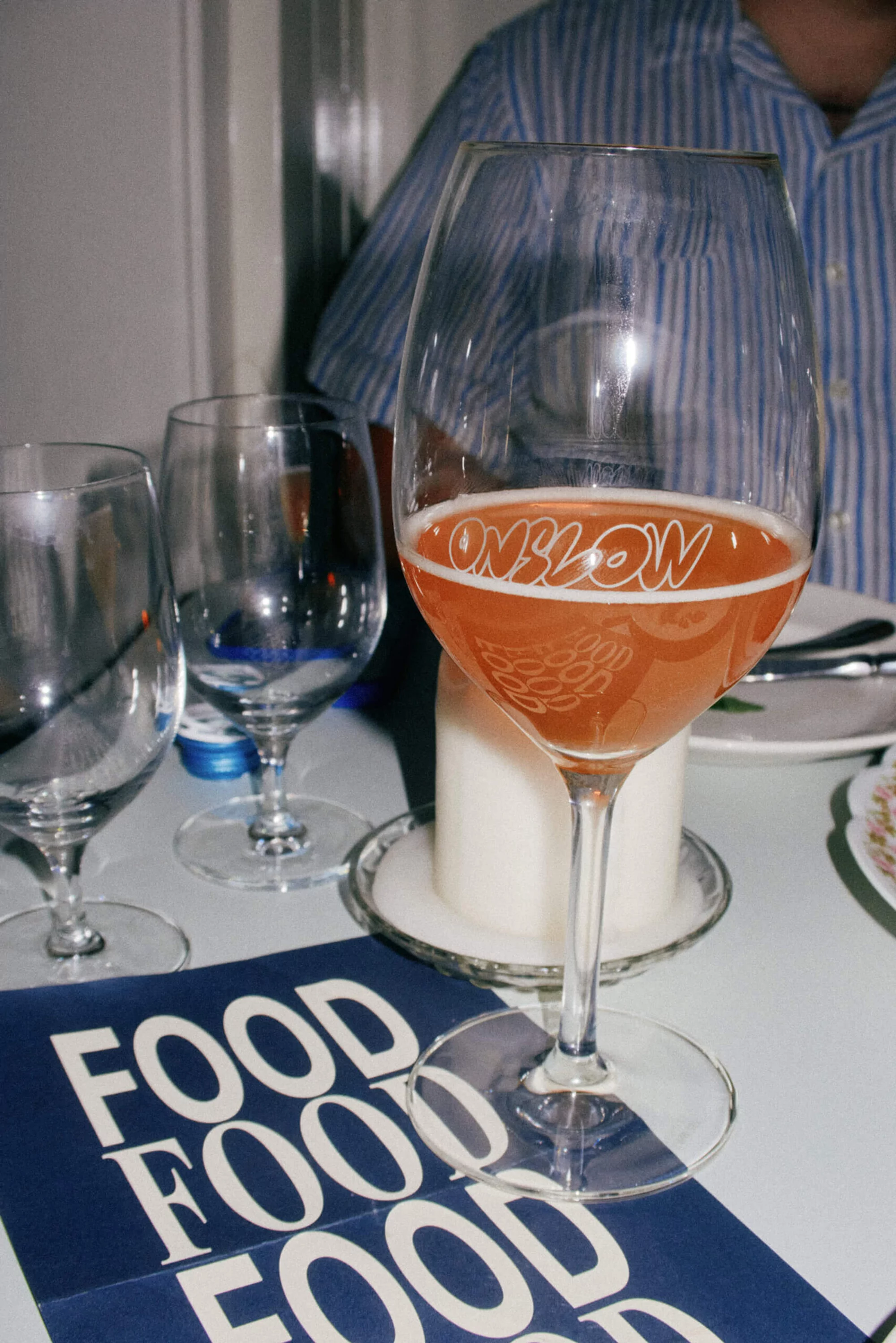 Wine glass filled with pink beverage on table with food menu and other glasses, set in an indoor dining environment.