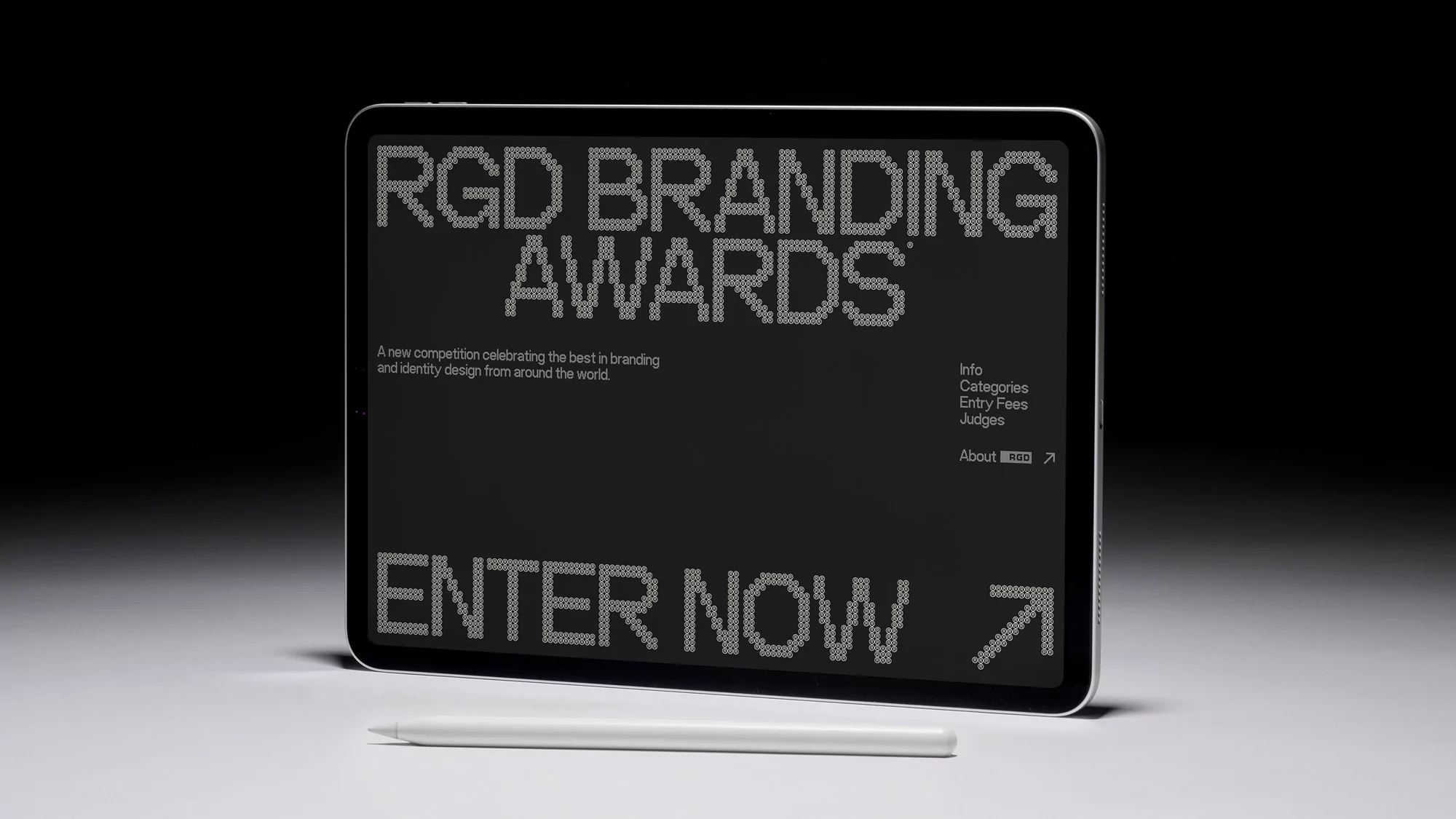 Black screen of a tablet displays RGD Branding Awards with 'Enter Now' below, accompanied by a white stylus on a white surface.