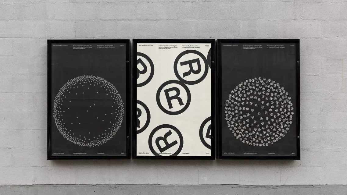 Three black-framed posters hang on a concrete wall. The posters showcase graphic designs featuring dots and the letter R within circles.