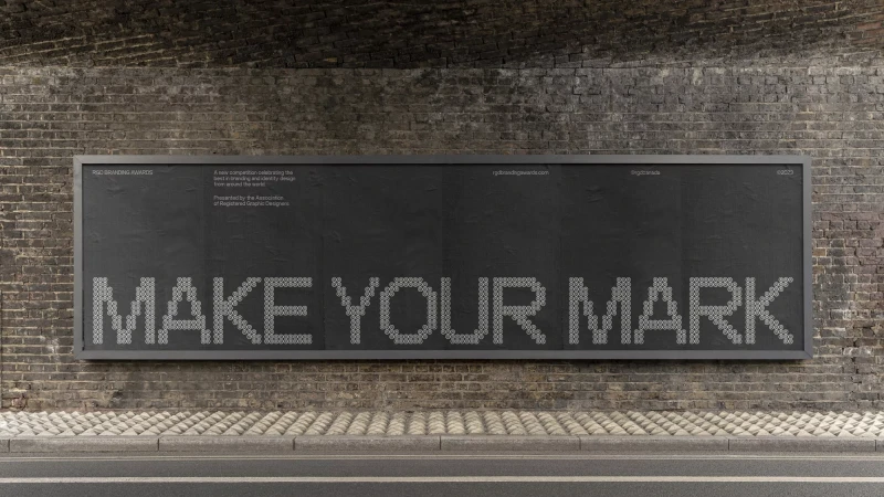 Outdoor advertising billboard on a brick wall displaying 'MAKE YOUR MARK' spelled out in small white circles for RGD Branding Awards.