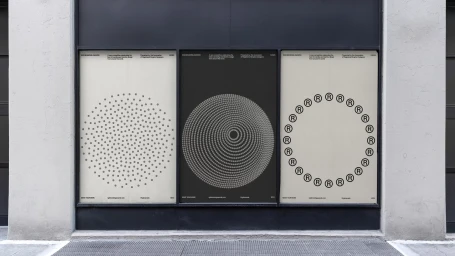 Three vertical posters featuring geometric and typographic branding designs displayed inside a storefront window.
