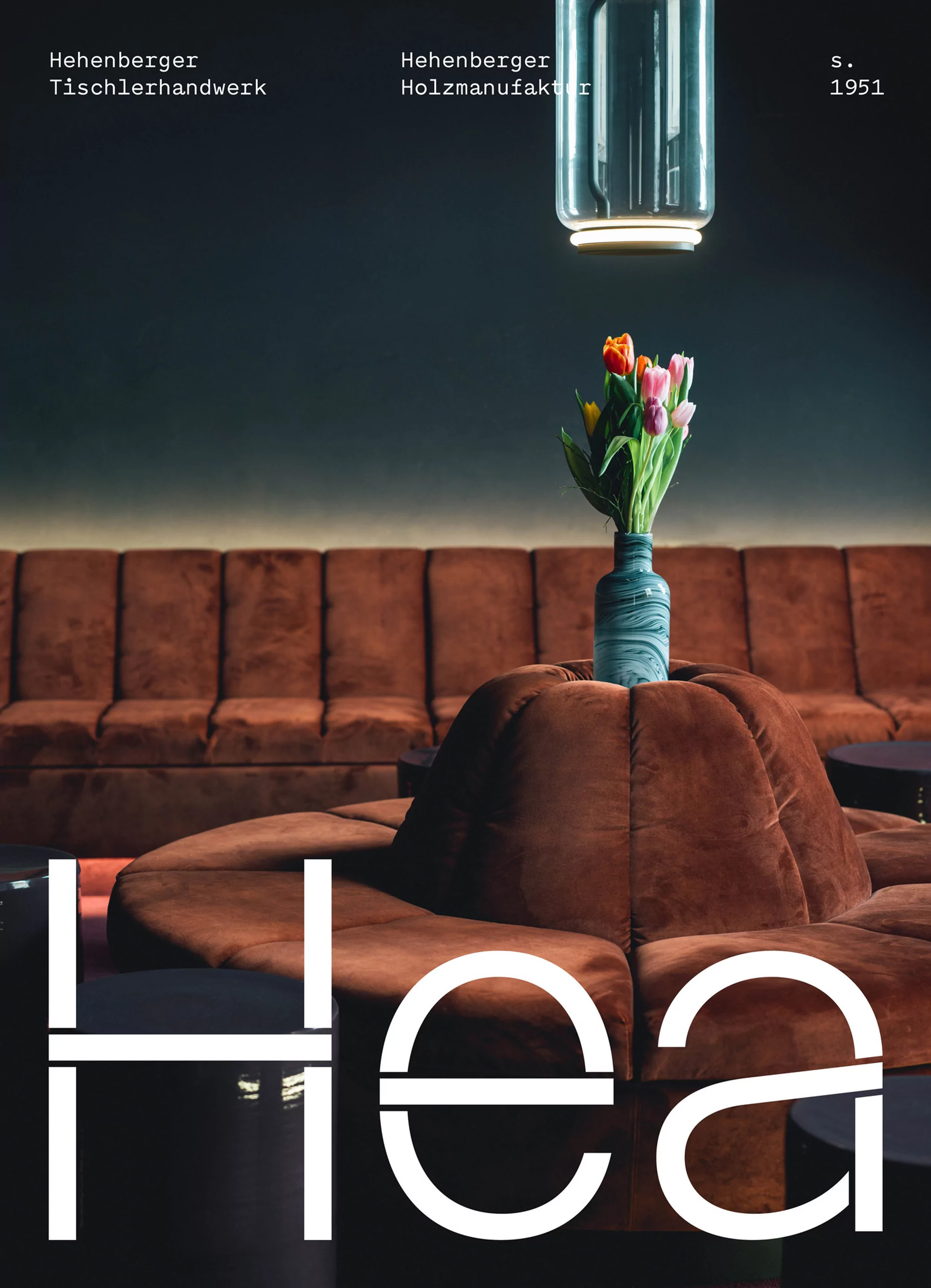 Interior space featuring a brown velvet sofa, a blue vase with tulips, and a modern light fixture, creating an elegant and inviting ambiance.