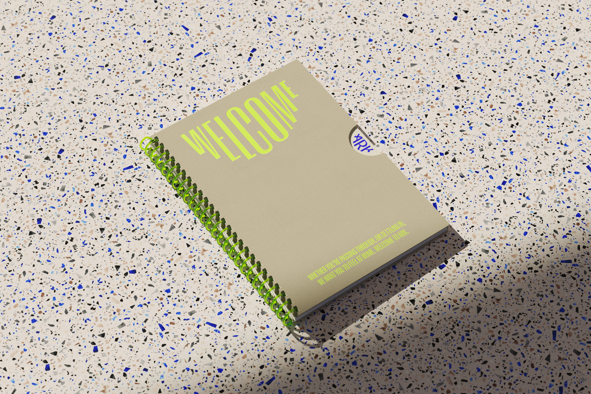 Close-up of a spiral-bound notebook with a beige cover and bright green binding, featuring 'WELCOME' in light green text.