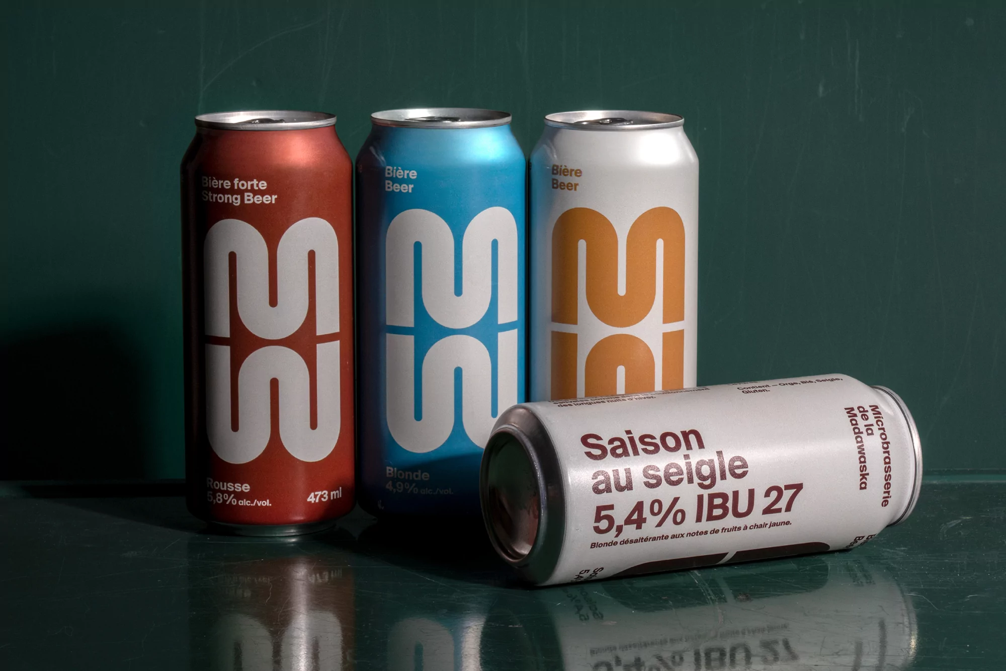 Four colorful aluminum cans of 22 Microbrasserie beer: one red, one blue, and two white, set against a dark green background.
