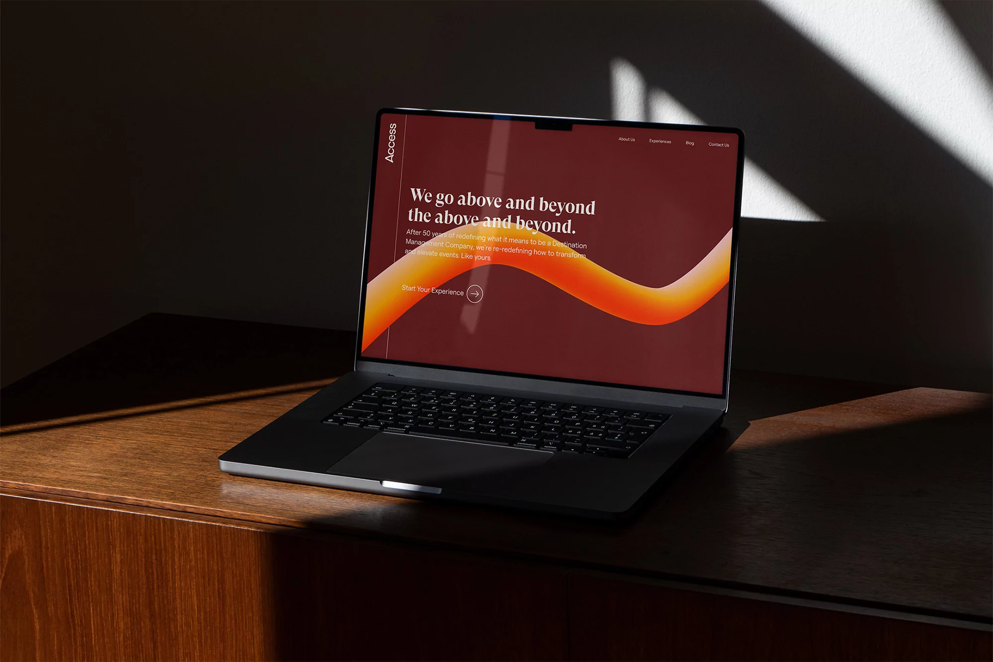 Laptop computer on a wooden desk displaying a website with the text 'We go above and beyond the above and beyond'.