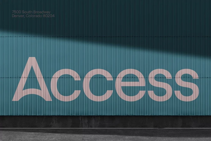Exterior shot of a teal corrugated metal building with the word ACCESS in light pink lettering. The building address is visible above.