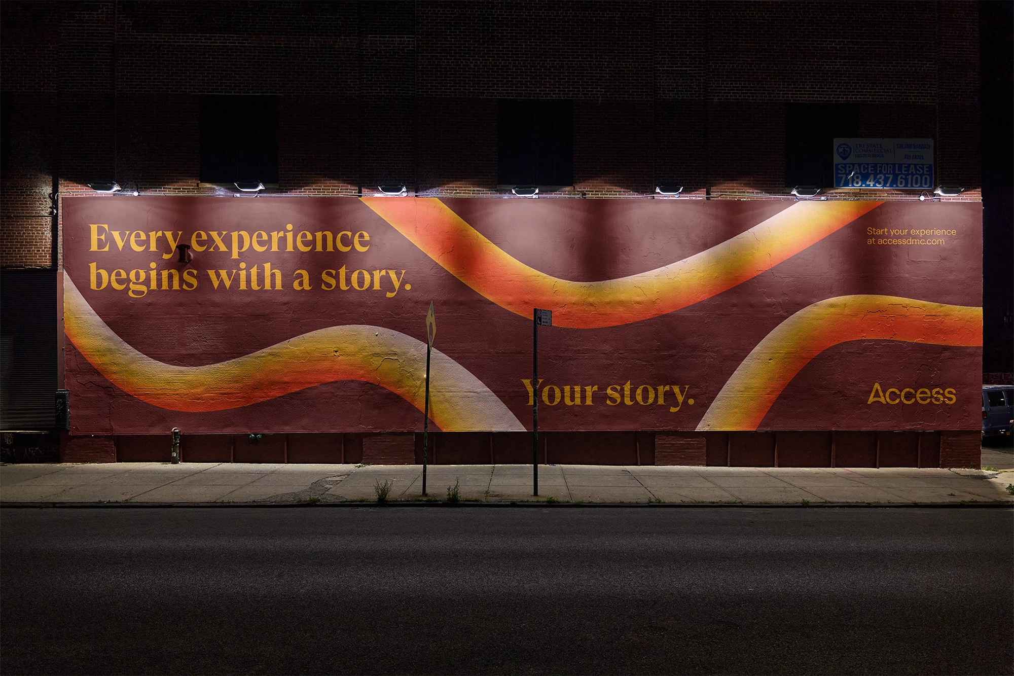 Outdoor night view of a large billboard on a brick building featuring an advertisement with text and orange and white graphic elements.