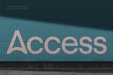 Teal corrugated metal wall with large pink Access typography and address text in Denver, Colorado