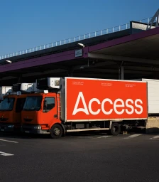 Orange freight truck with Access branding parked outside a warehouse loading dock
