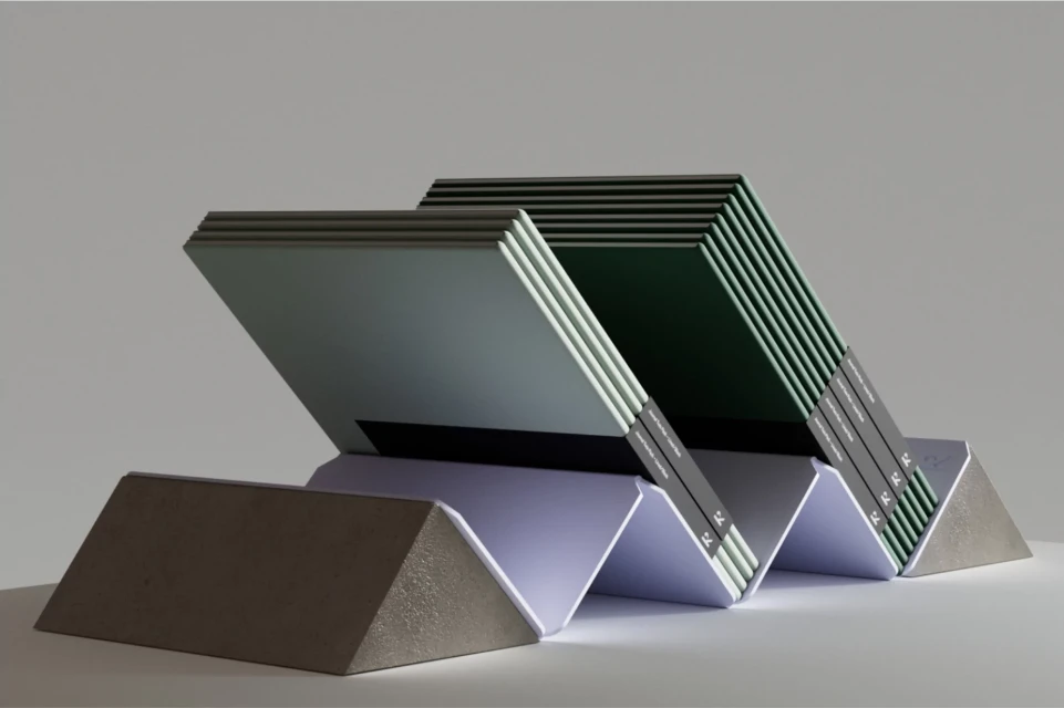 A stack of paper arranged accordion-style in gray and green tones on a white surface, with concrete stands on both ends.