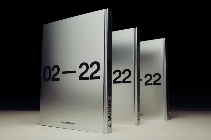 Three silver books stand in a row against a black background, displaying large, bold, black numbers '02-22' on their covers.