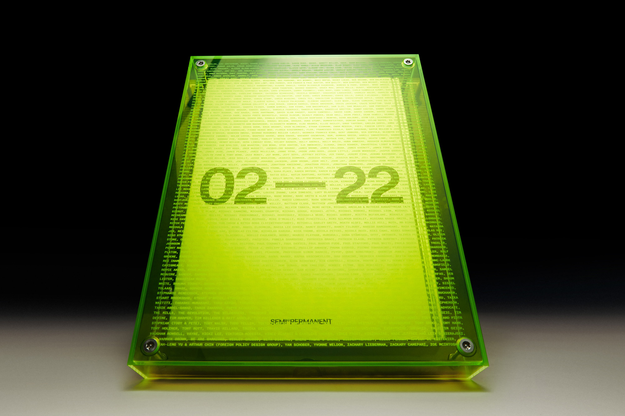 Abstract neon yellow display featuring the numbers '02-22' and brand 'Semi-Permanent' encased in a transparent frame, studio shot.