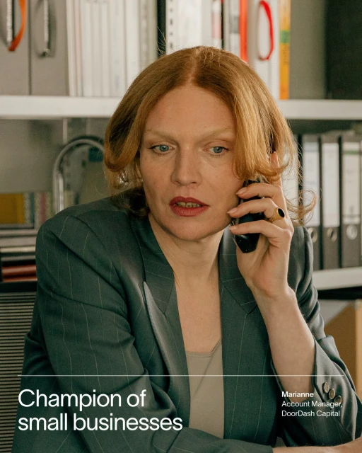 Professional woman in pinstripe suit on a phone call in an office setting. Businesswoman with auburn hair. Office interior background.