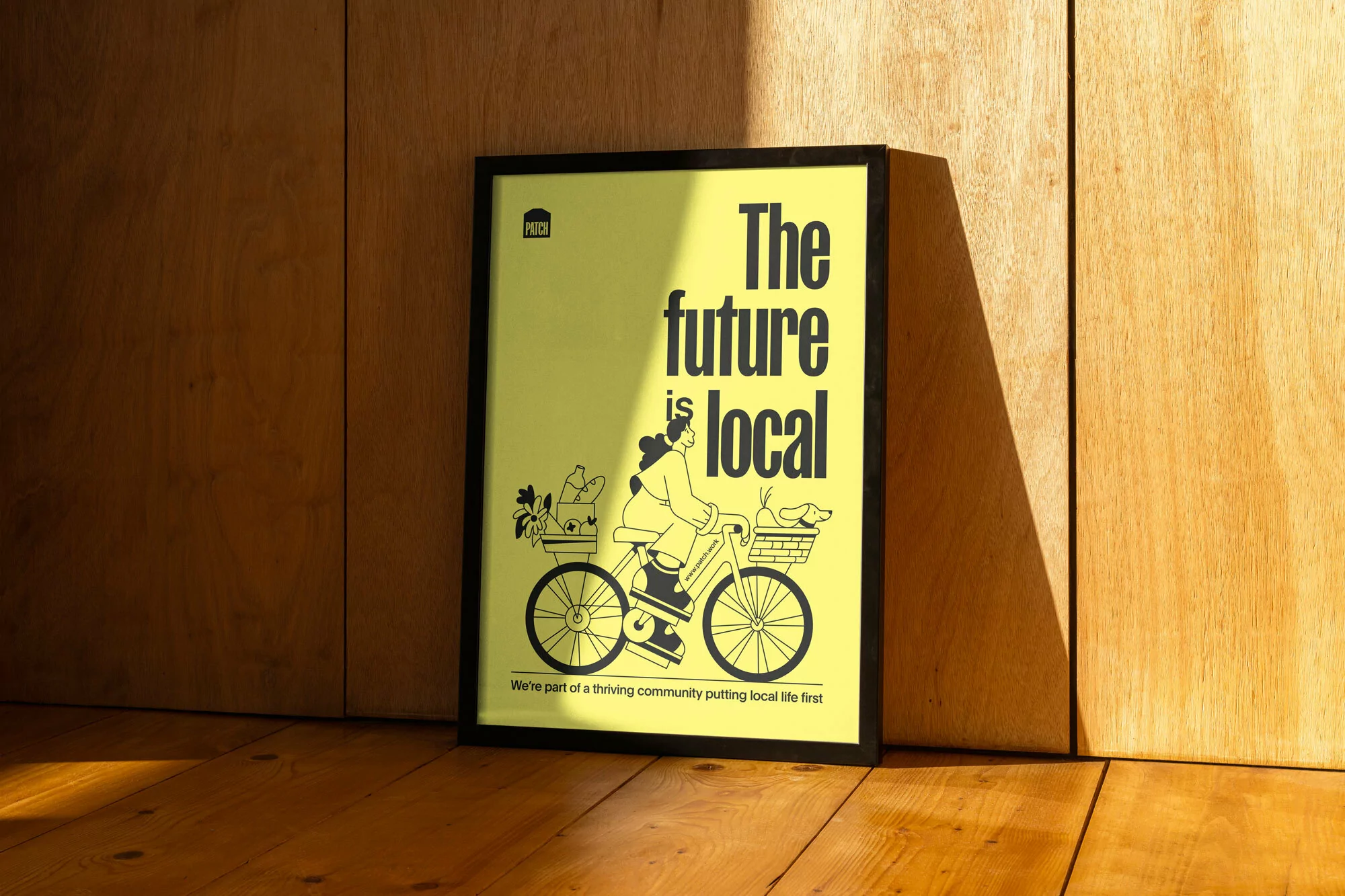 Graphic design poster featuring an illustration of a woman on a bicycle with the text 'The future is local', displayed indoors.
