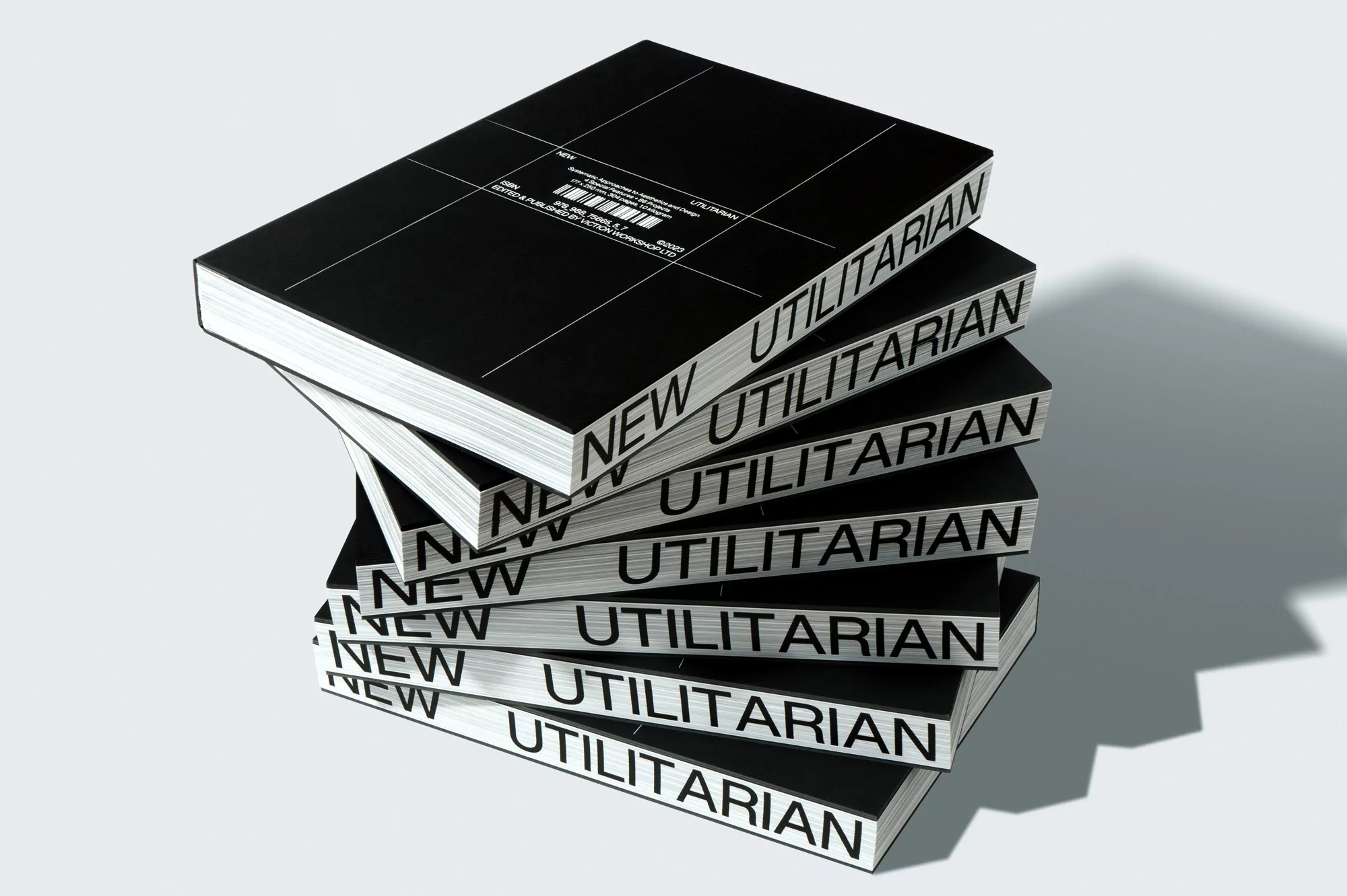 Stack of black hardcover books titled 'New Utilitarian' with white text, arranged on a white surface with subtle shadow.
