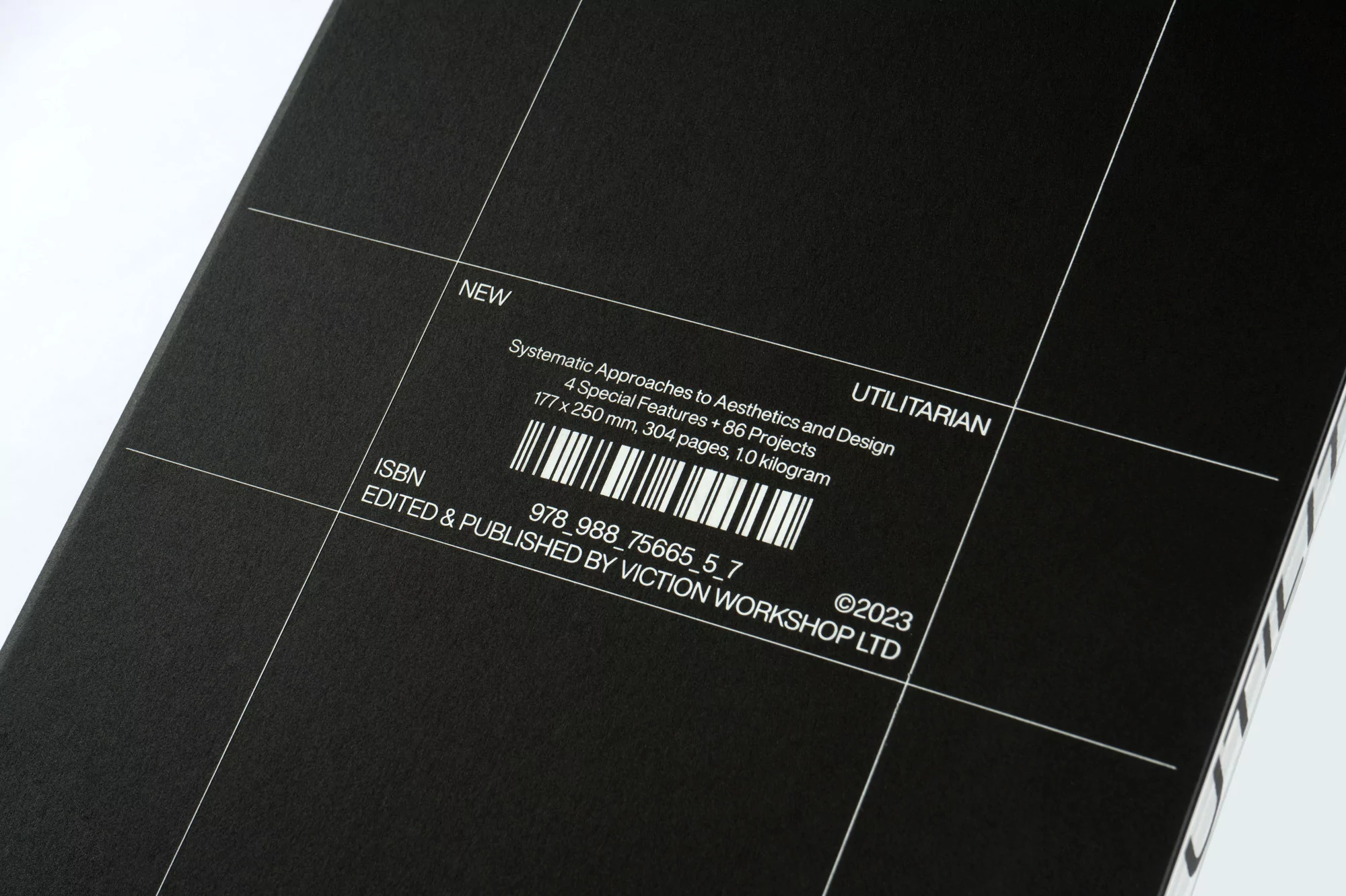 Close-up of a black book cover with white typography and a grid design, featuring the word 'UTILITARIAN' and a barcode.