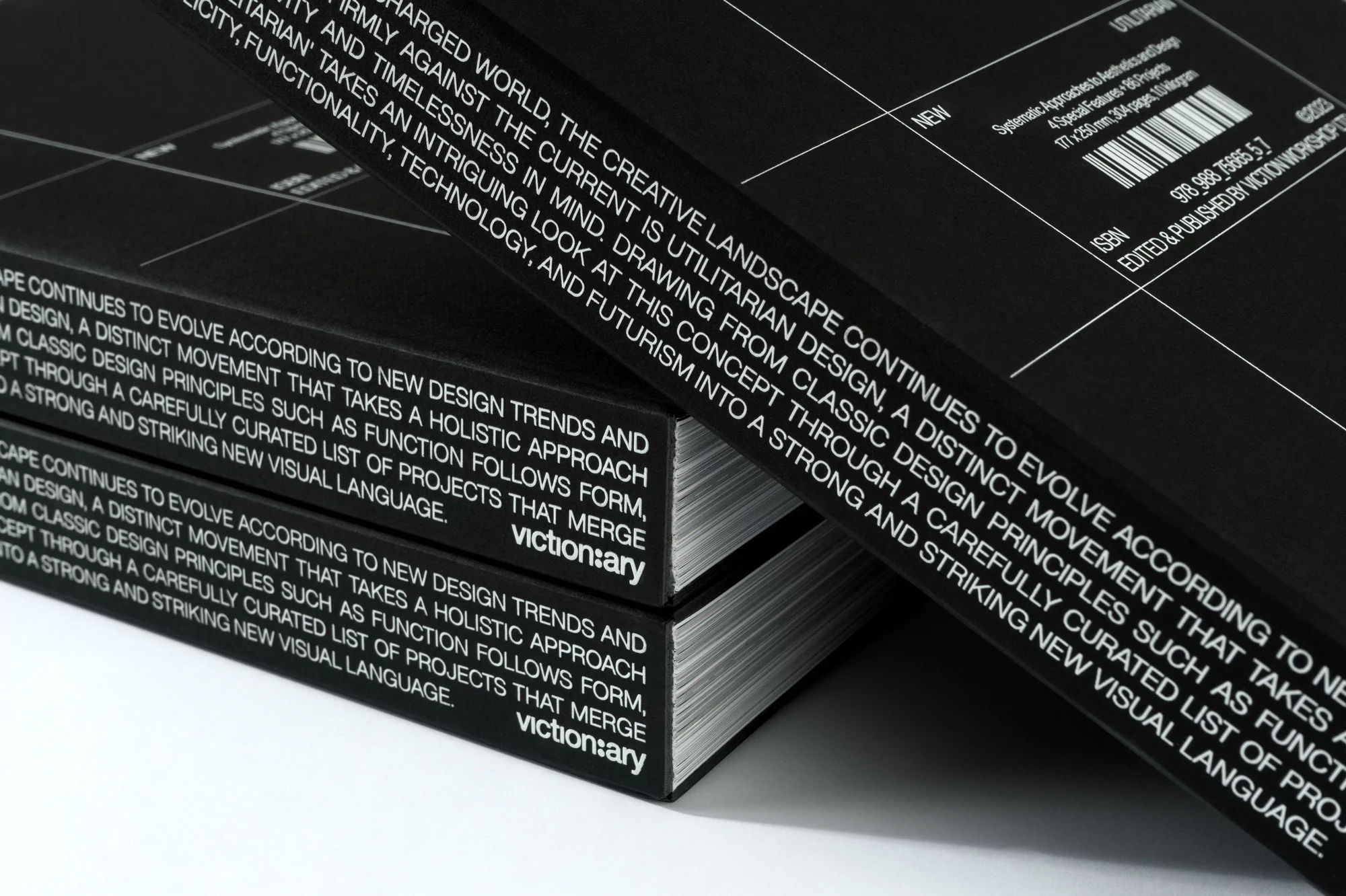 Two black books titled "victionary" stacked on a white surface, with text describing design principles and movements visible.