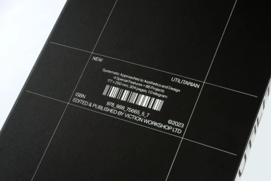 Close-up of a black book cover featuring white grid lines, typography, and a barcode for victionary brand identity project