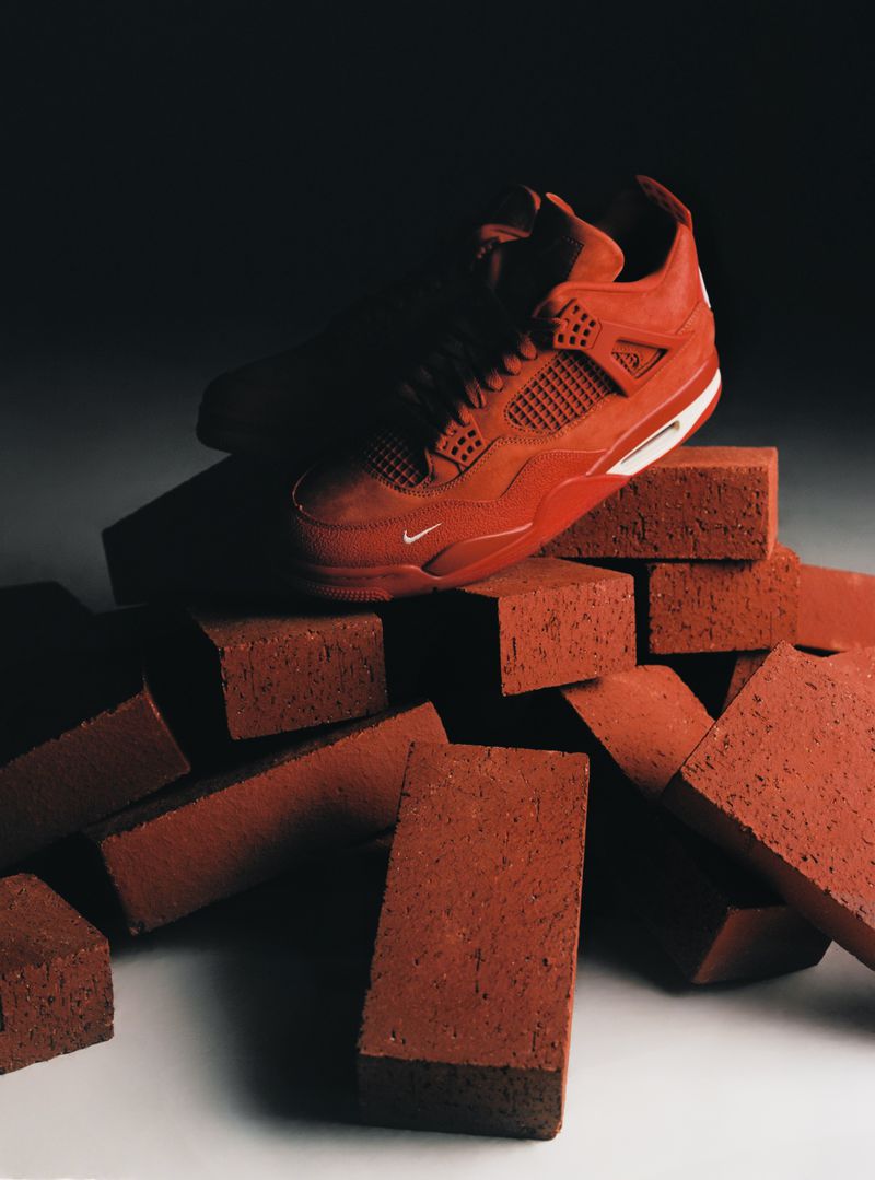 Red basketball shoe on a pile of red bricks in a studio with soft lighting. Athletic footwear product photography for social media.