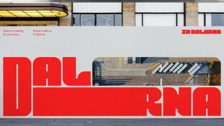 Bold red typography on a large white billboard featuring the text Dalarna alongside an aerial view of a parking lot.