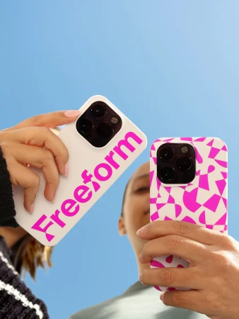 Two hands holding smartphones with custom cases against a clear blue sky.