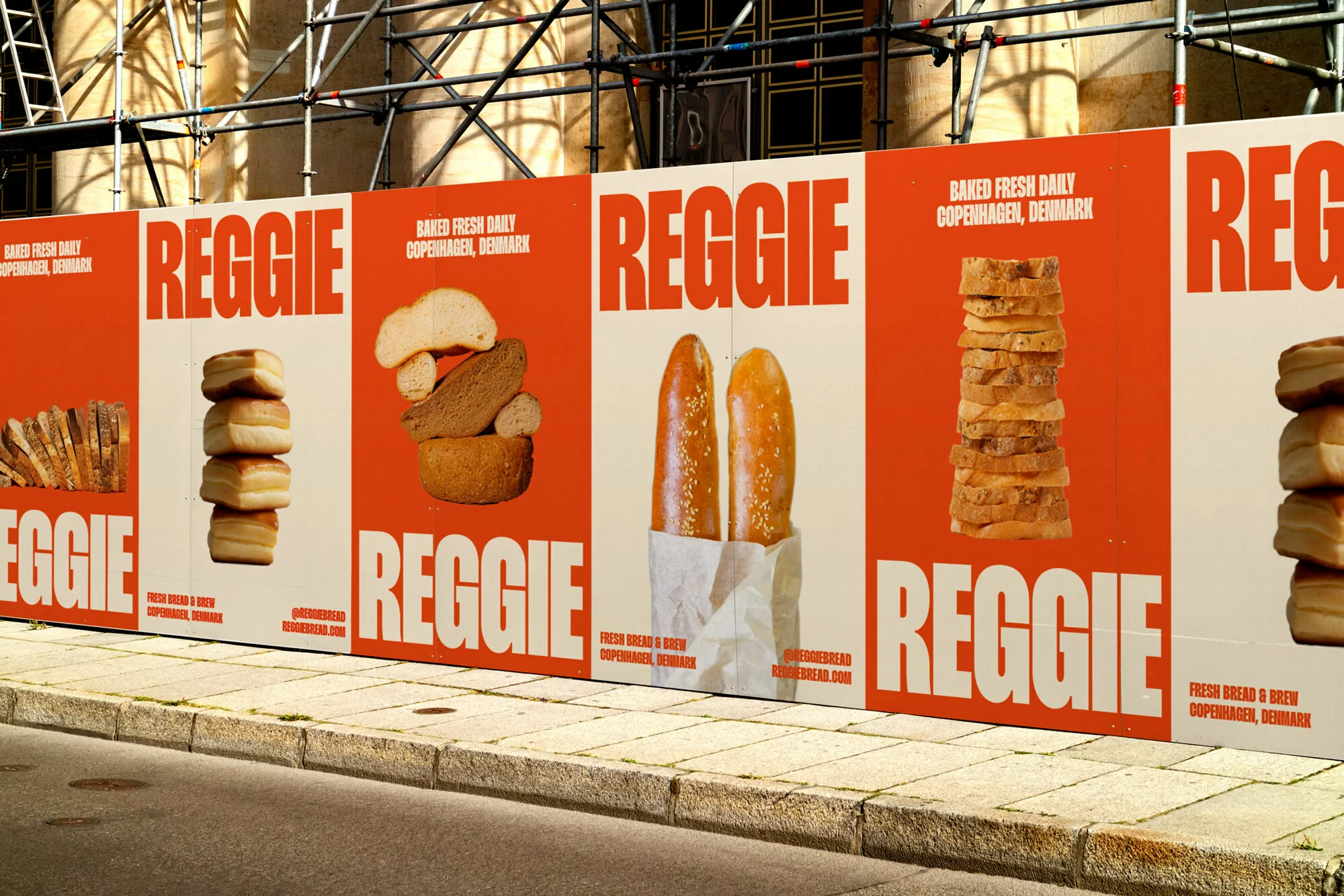 Street-level view of advertising hoarding with 'Reggie' bread ads featuring stacked bread loaves on an orange and white background.
