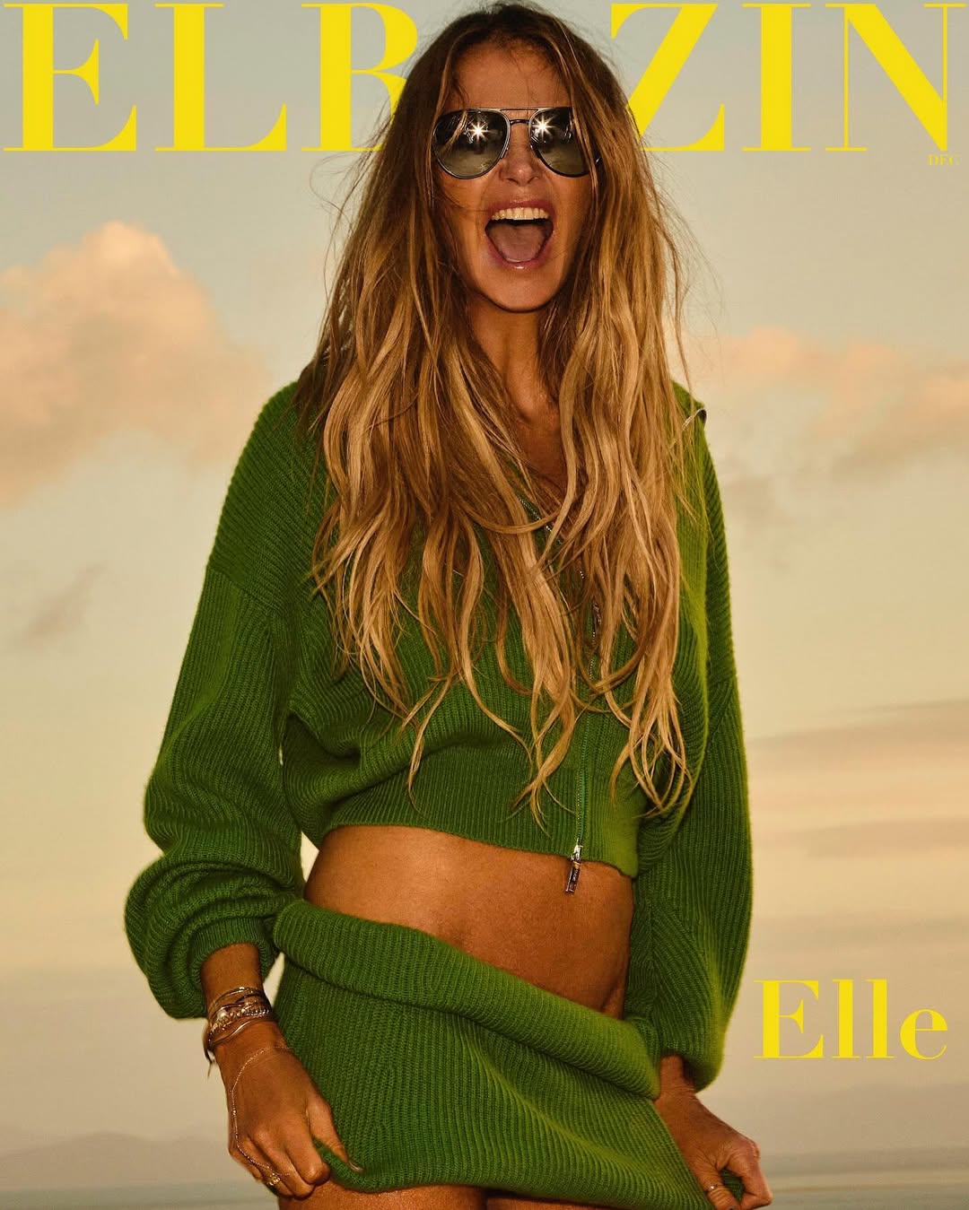 Magazine cover featuring a woman with long hair wearing sunglasses, a green knitted jacket and skirt, set against a bright, sunny outdoor backdrop.