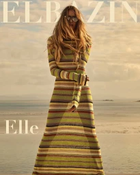 Woman in a striped maxi dress and sunglasses standing outdoors near water for Elbazin Magazine