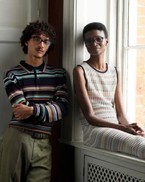 Two models posing near a window wearing striped apparel for the Paul Smith Spring 2025 collection.