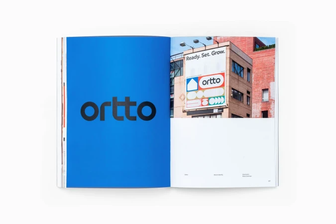 Spread from a brand identity publication showcasing a bold blue page with lowercase black typography and a building billboard photograph.