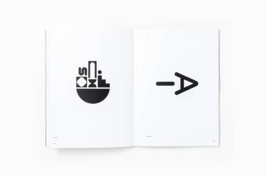 An open book displaying minimalist black geometric graphic designs on white paper pages.