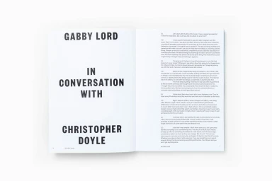 Open book spread showing bold black sans serif title text on the left and interview transcript on the right against a plain surface.