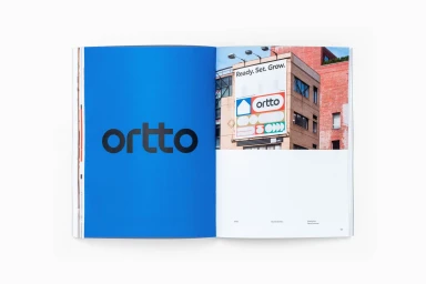 Spread from a brand identity publication showcasing a bold blue page with lowercase black typography and a building billboard photograph.