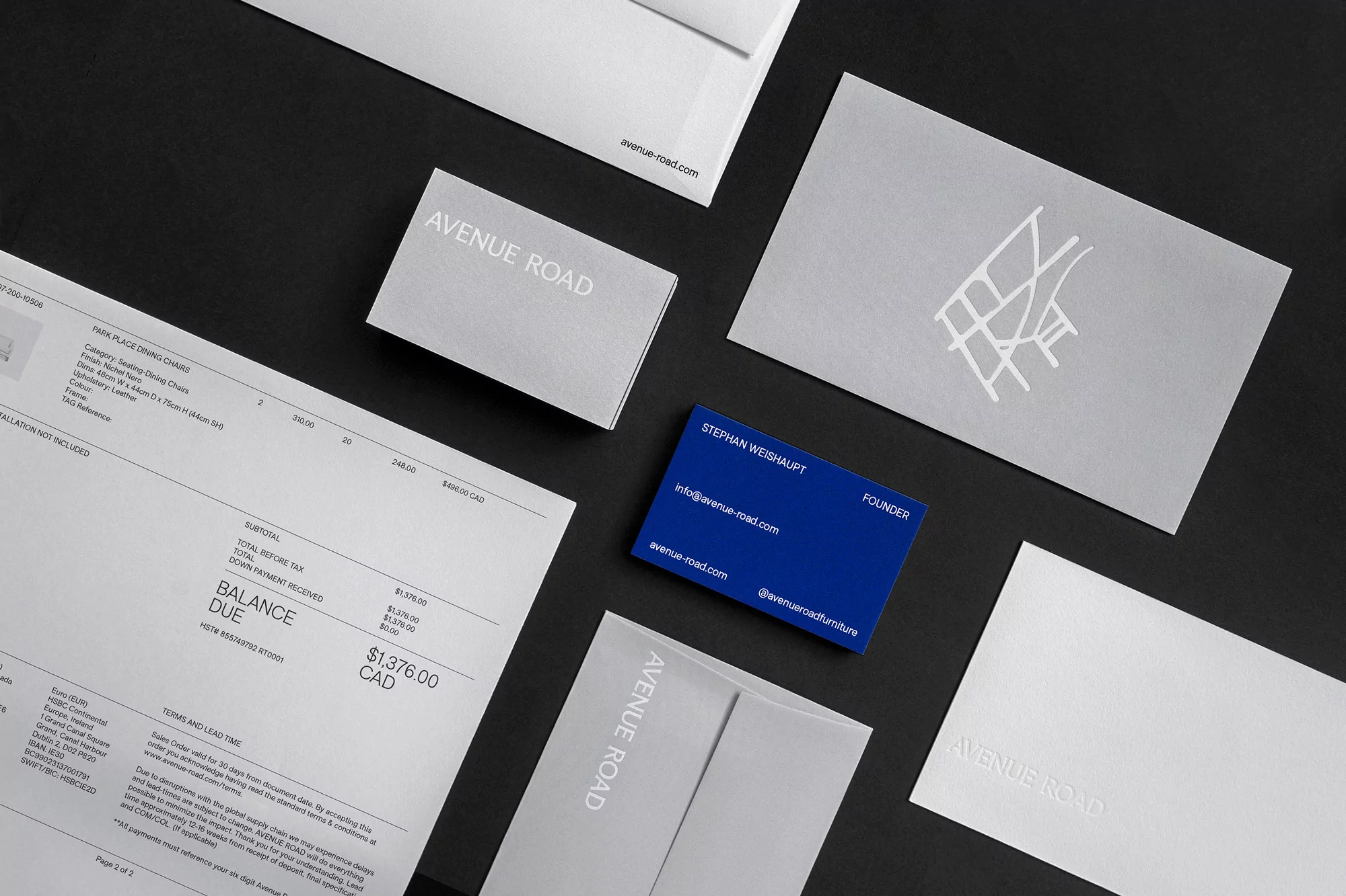 Stationery set of Avenue Road branded items in a flat lay: envelopes, invoices, and business cards, arranged on a black surface.