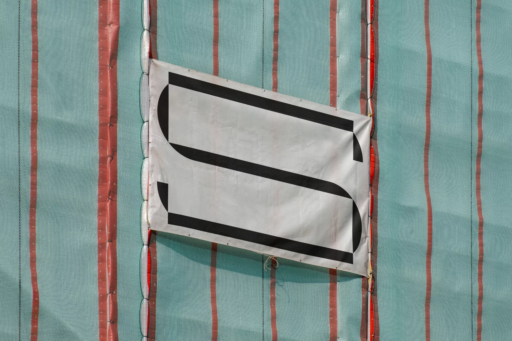 Fabric screen with a white banner displaying a black 'S' shape, creating a simple, graphic construction-themed image.