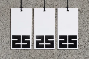 Three white price tags hanging against a textured grey concrete wall surface.
