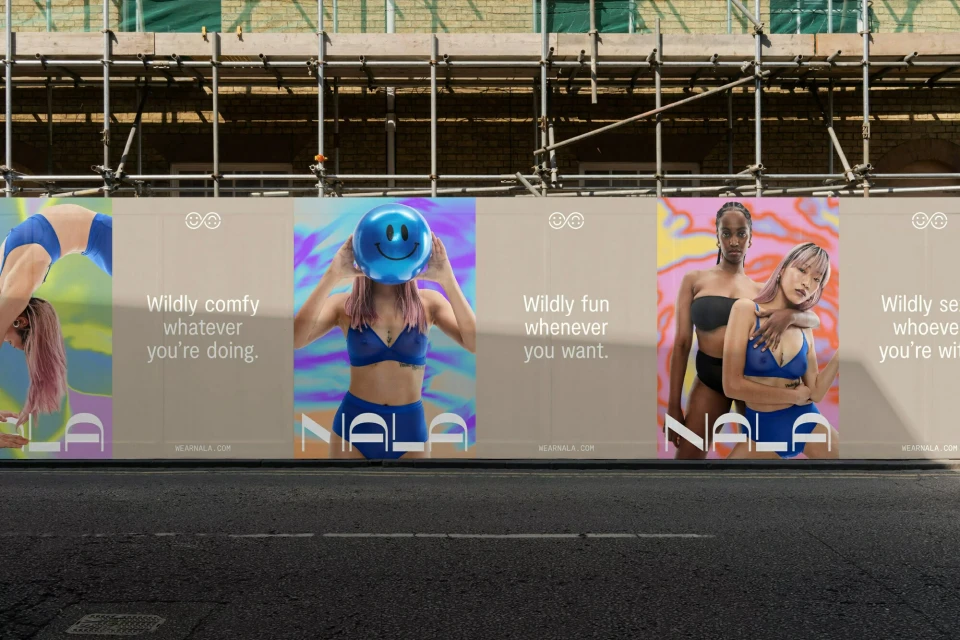 Eye-level shot of an outdoor ad campaign featuring two women embracing each other in swimwear and confident messaging.