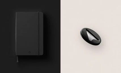 Black notebook on a solid black background alongside a sleek oval metallic object on a cream background