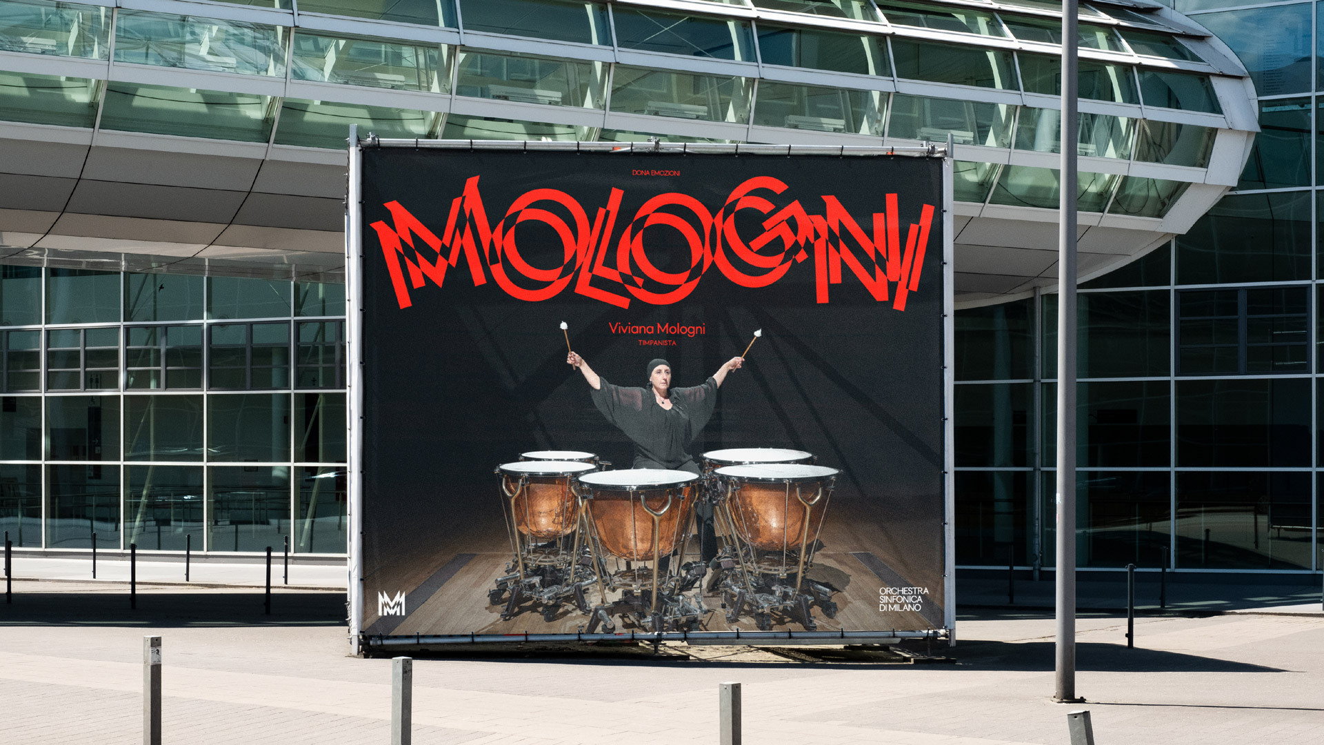 Outdoor banner showing a woman playing timpani drums in front of a modern building, promoting Viviana Mologni and the Orchestra Sinfonica.