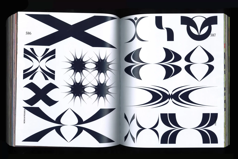 Open book displaying black and white graphic design elements including radial, crisscross, and symmetric patterns on facing pages.