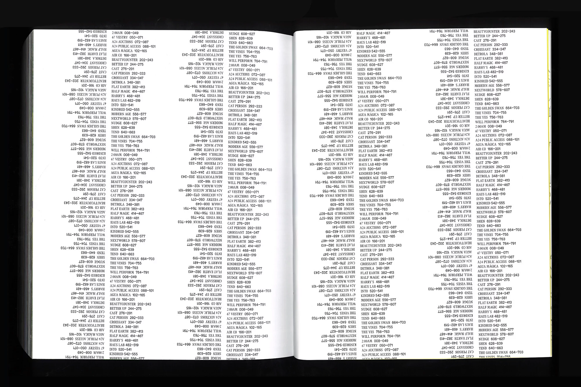 Open book shows densely-packed pages filled with black text arranged in columns, set against a black background. Focus is on readability.