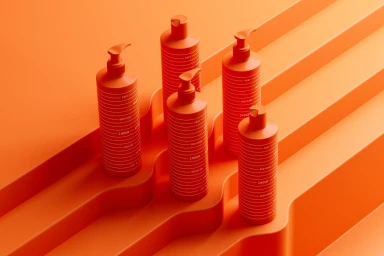 Five orange skincare bottles with pump dispensers arranged on a textured orange geometric stepped platform