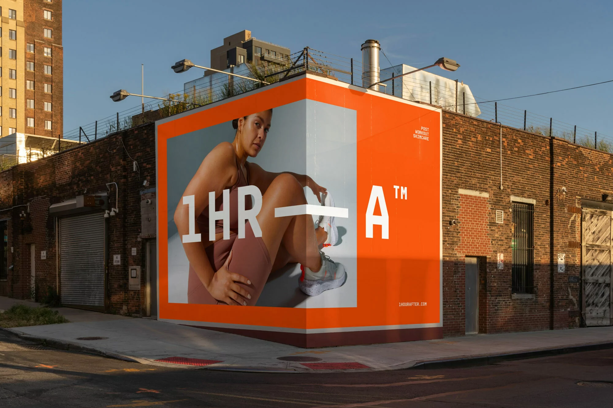 Outdoor advertising: Billboard with an image of a woman in activewear. The billboard is on a brick building on a city street.