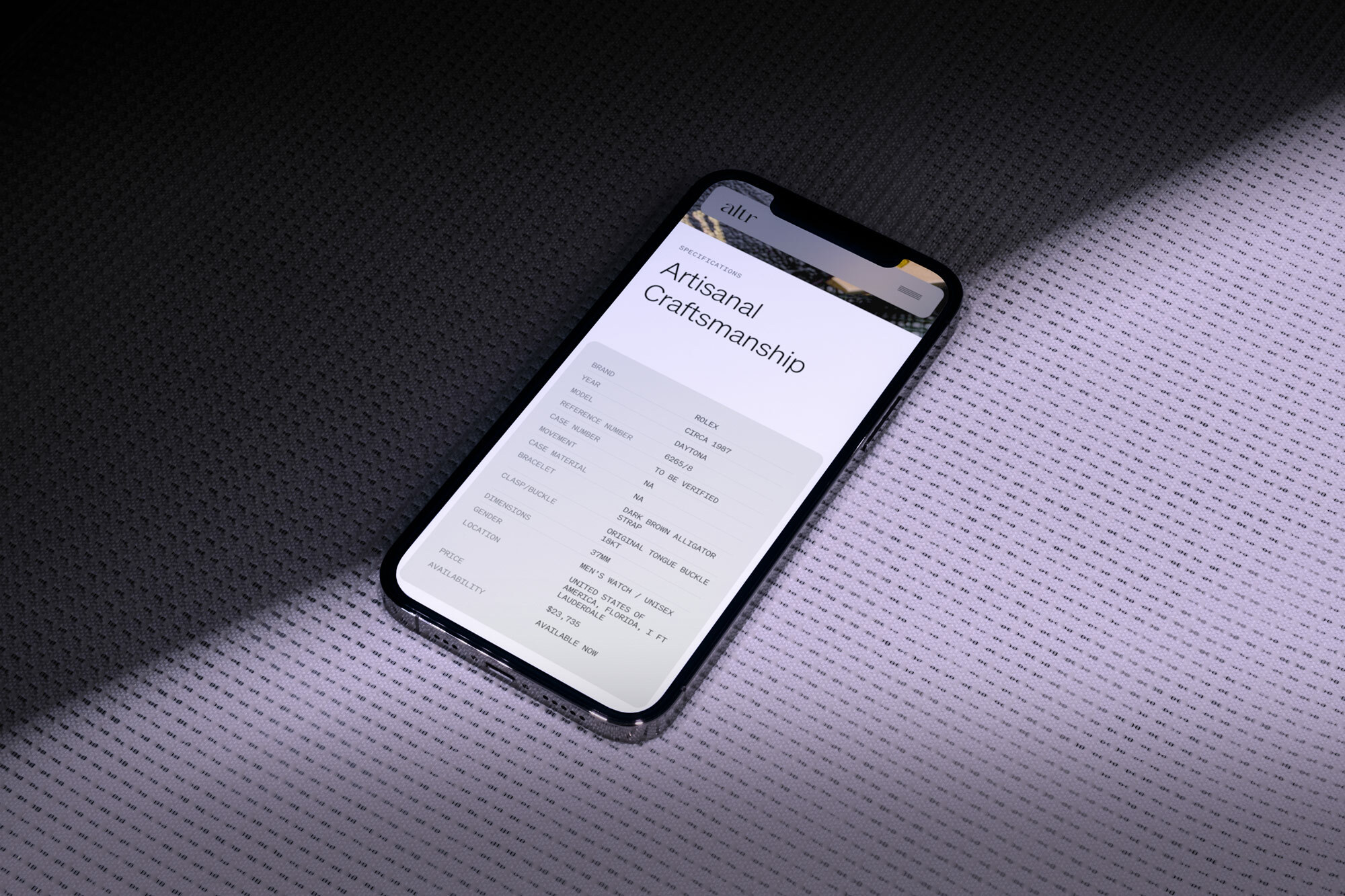 An iPhone displays an article about artisanal craftsmanship on a textured gray surface in studio lighting, creating a high-tech, sleek composition.