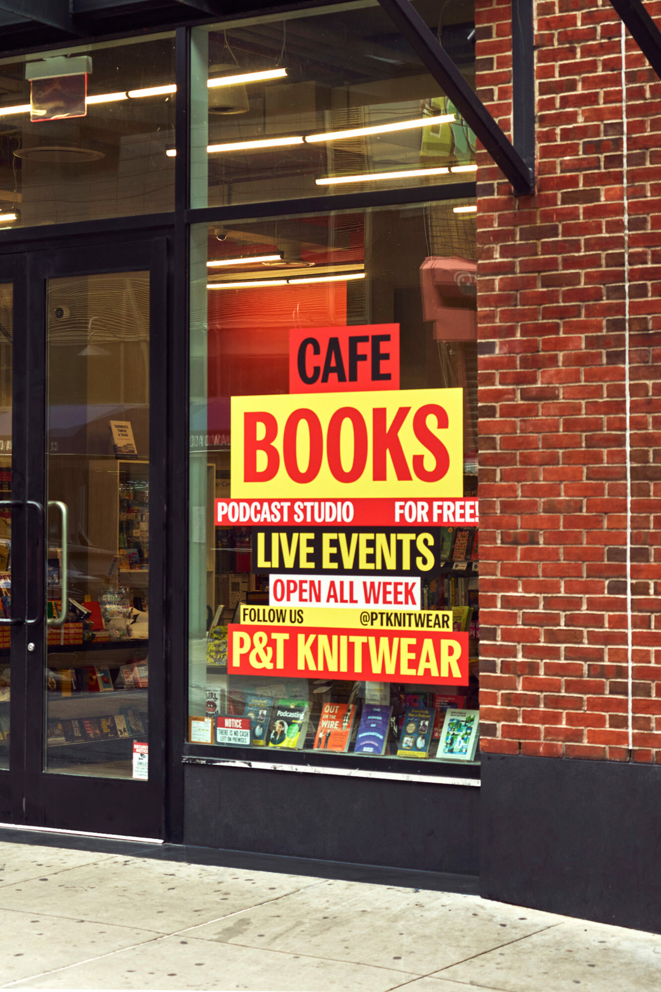 Exterior view of a bookstore with large red and yellow signage advertising books, podcast studio, and live events in an urban setting.