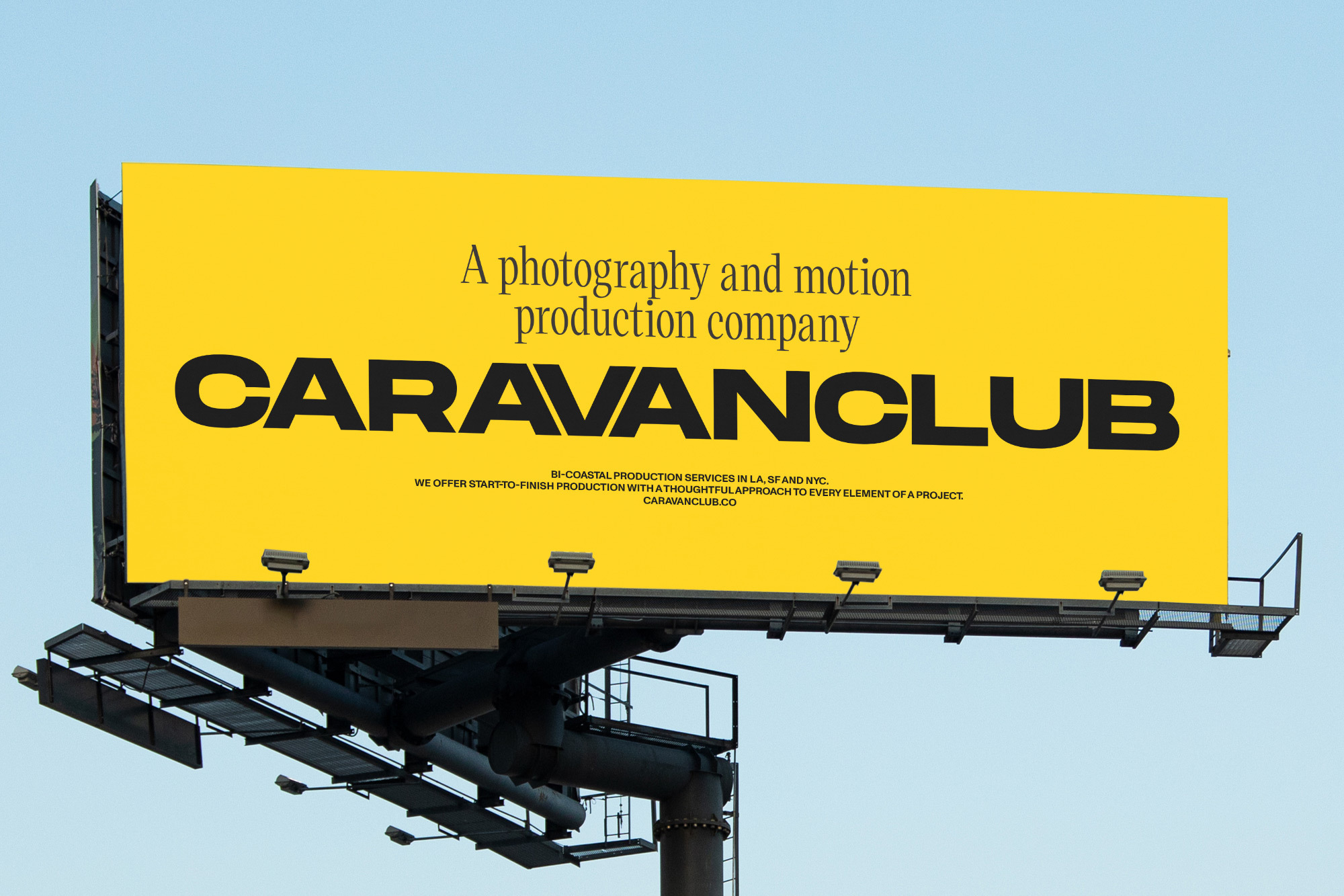Billboard advertisement for Caravanclub, a photography and motion production company, against a clear blue sky. Focus on brand promotion.