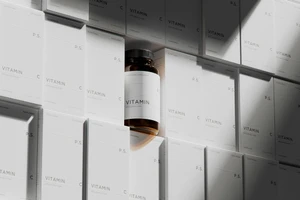 Amber glass vitamin bottle centered among clean white minimalist packaging boxes under dramatic directional light