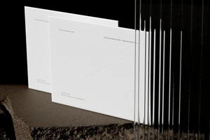 Two clean white stationery folders resting on a dark textured stone surface with fluted glass on the right