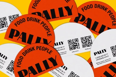 Close-up of overlapping bright orange and white semi-circular business cards and stickers displaying bold typography.